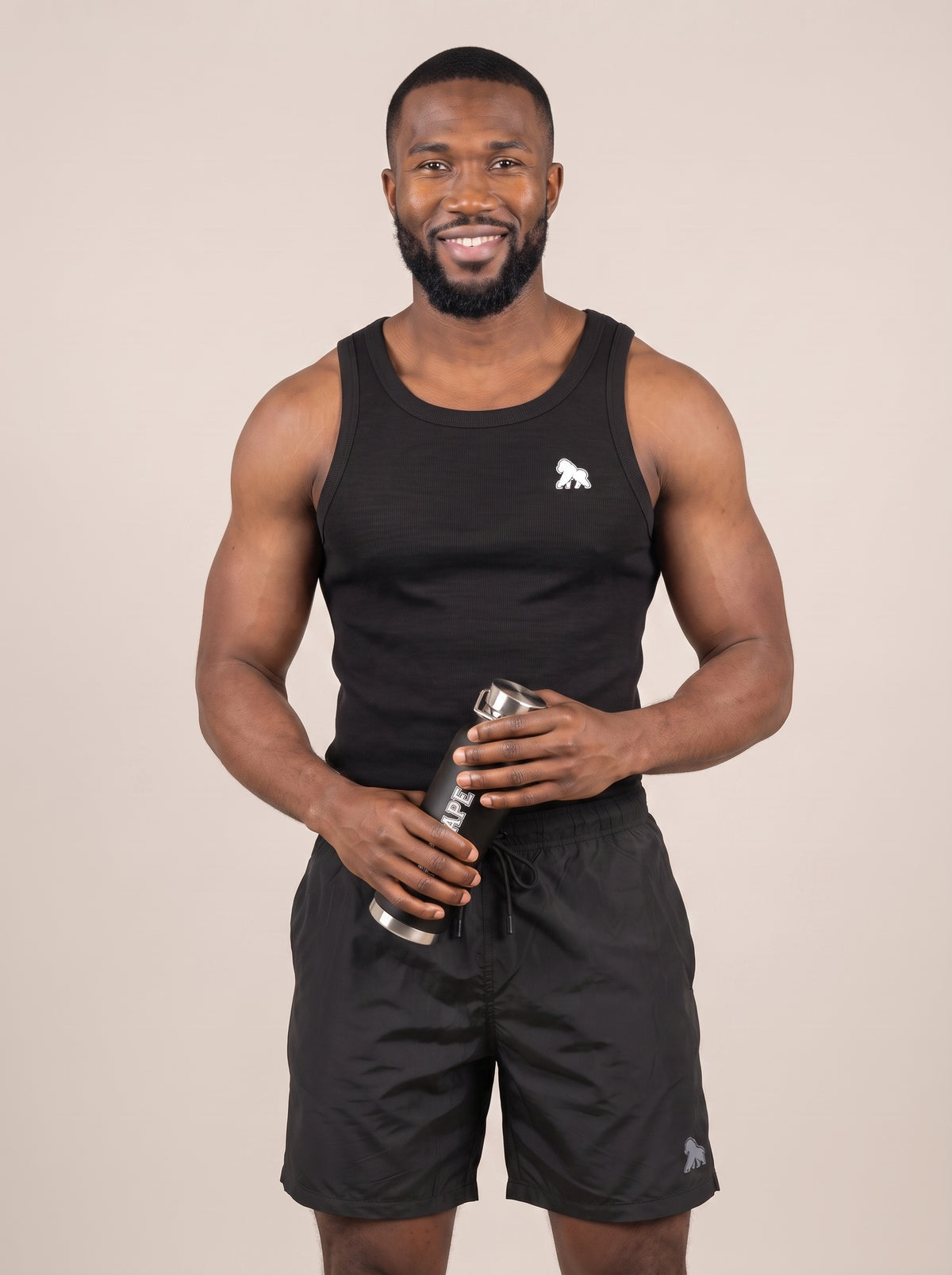 Model in black gym clothing holding a FIT APE water bottle with both hands
