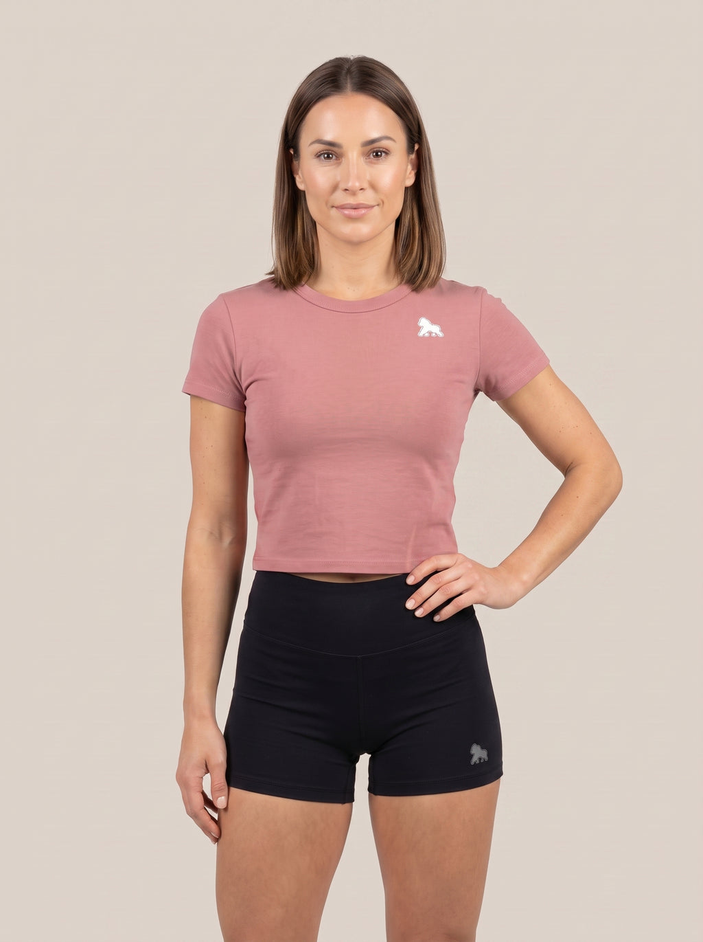 Pink FIT APE women's cropped performance top on a model with one hand on her hip