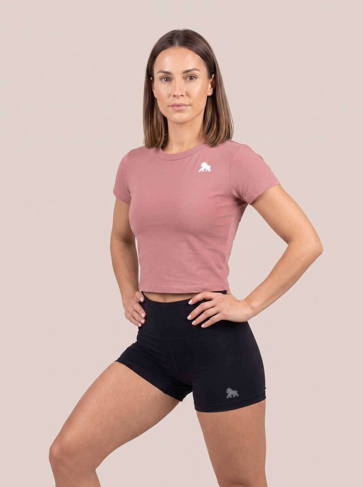 Pink FIT APE women's cropped performance top on a model posing with a bent knee