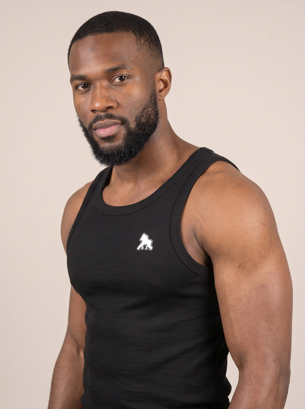 Close-up of a black FIT APE men's tank top on a model, showing the white chest gorilla