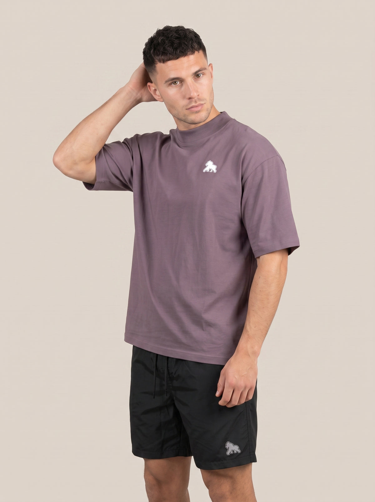 Muted purple FIT APE men's oversized tee on a model with one hand behind his head