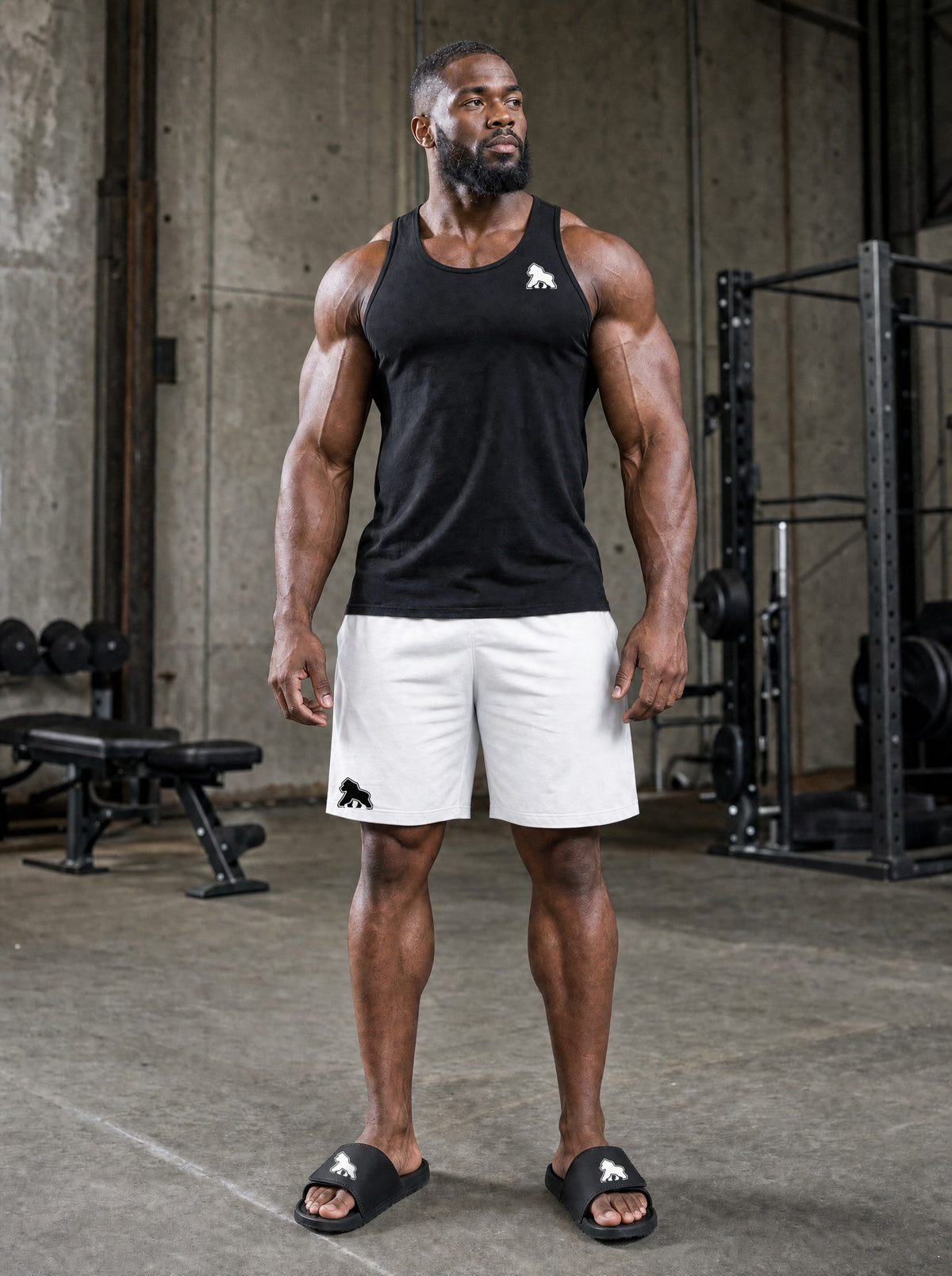 Muscular male athlete in a FIT APE tank and shorts wearing black FIT APE Recovery Slides in the gym