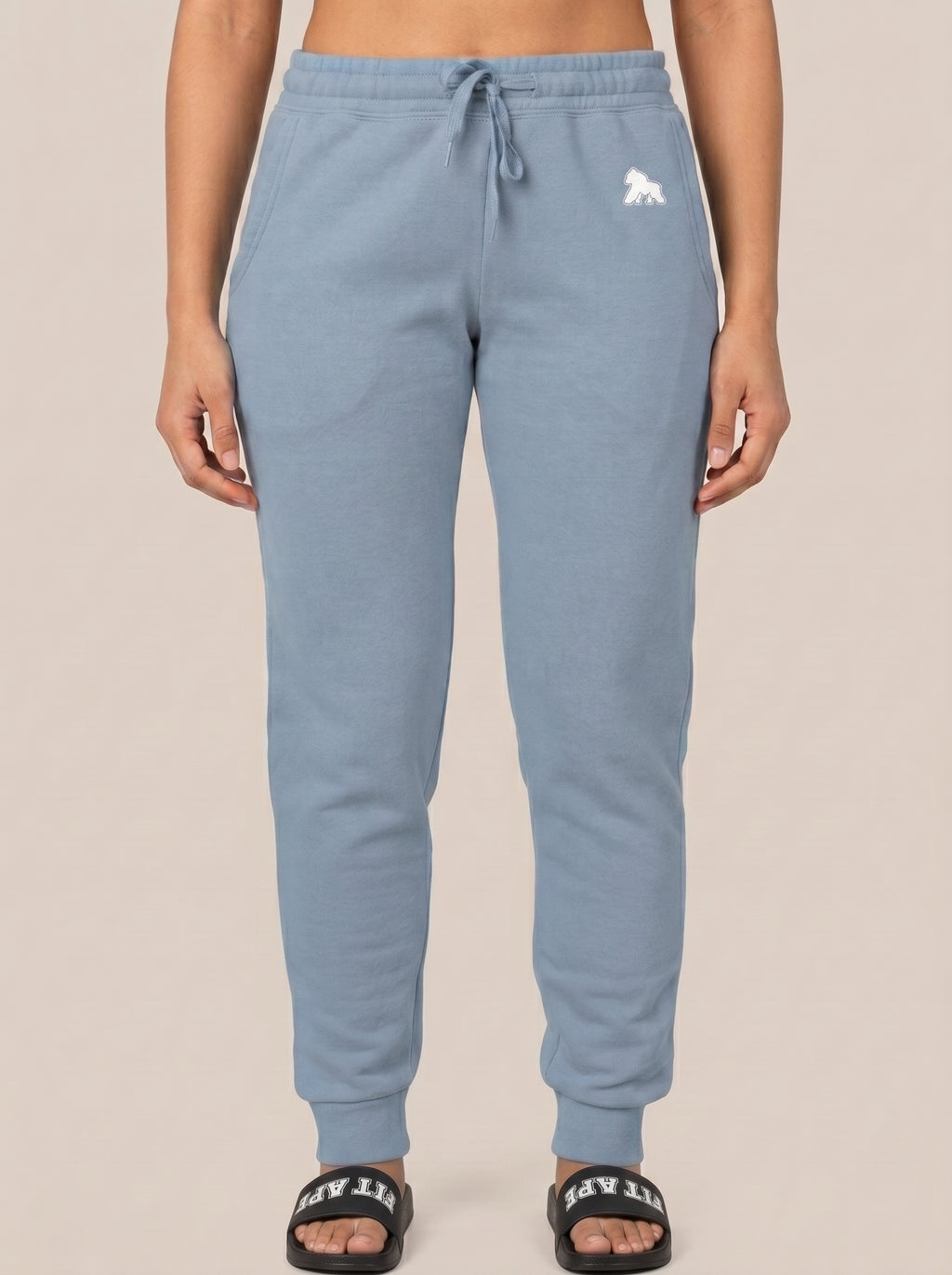 Model in blue joggers wearing black FIT APE slides, front standing view