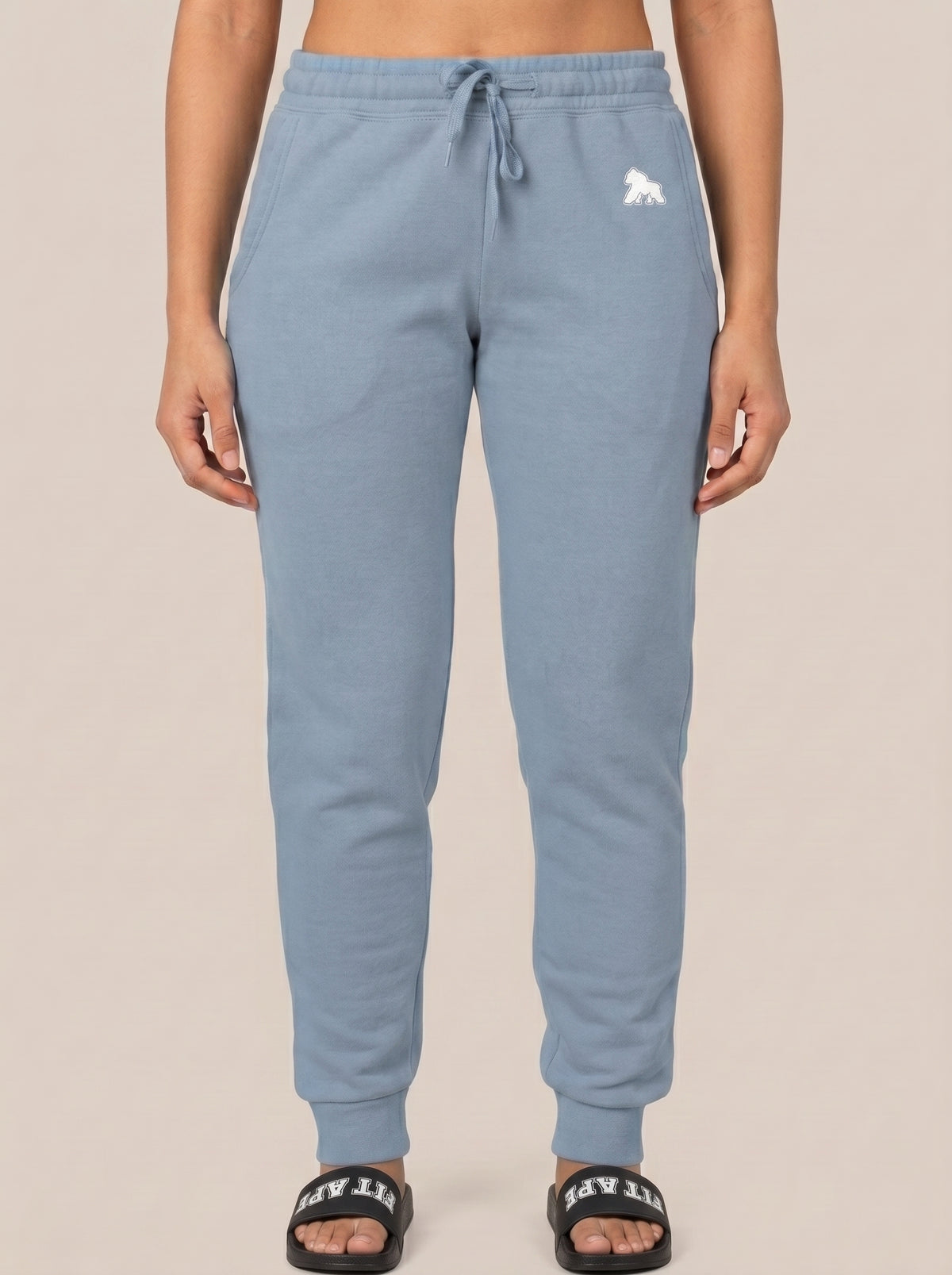 Model in blue joggers wearing black FIT APE slides, front standing view