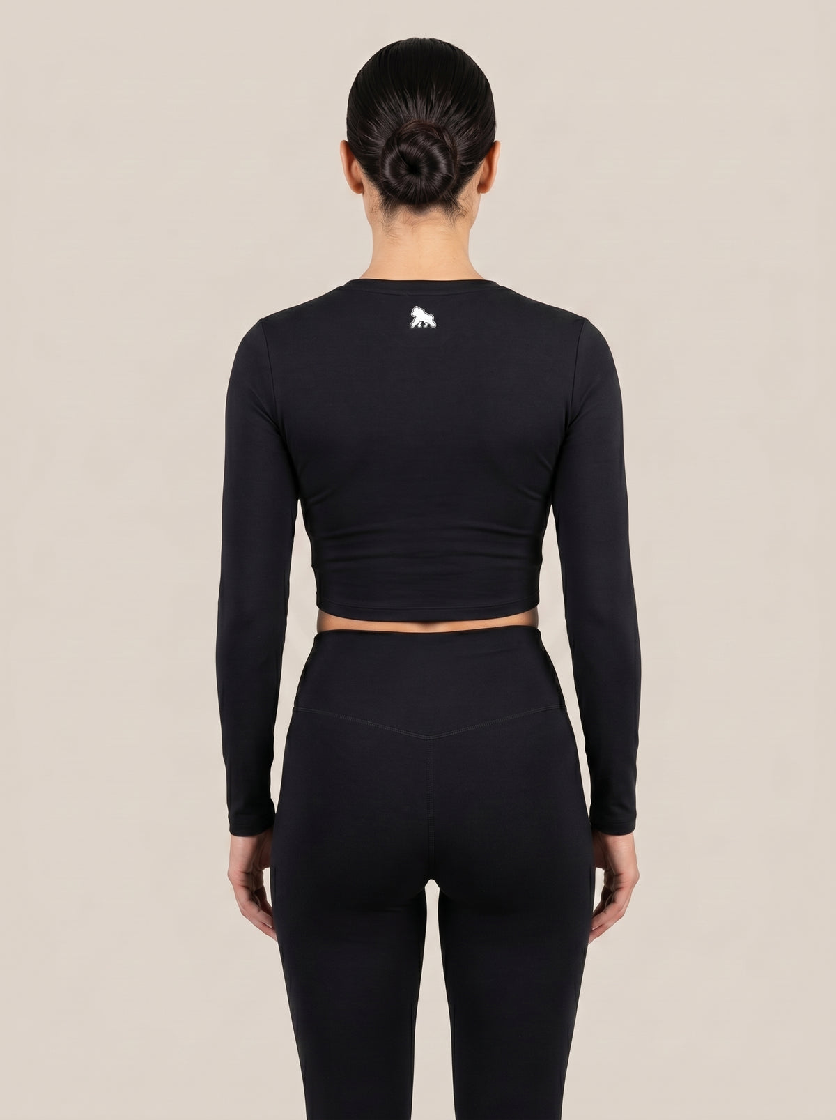 Black FIT APE women's long-sleeve compression crop top on a model, back view