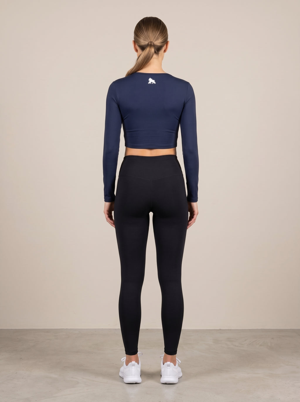 Navy FIT APE women's long-sleeve compression crop top on a model, back view
