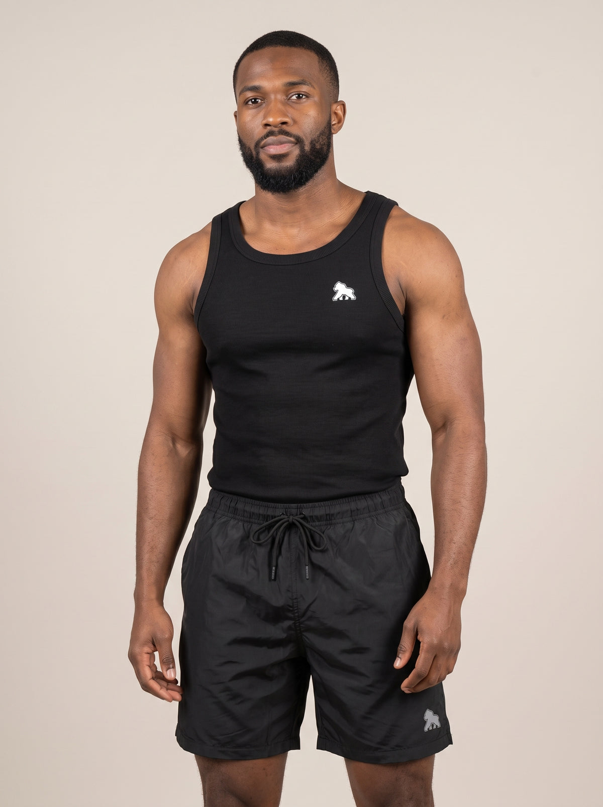 Model wearing a black FIT APE men's tank top with white chest gorilla, front view