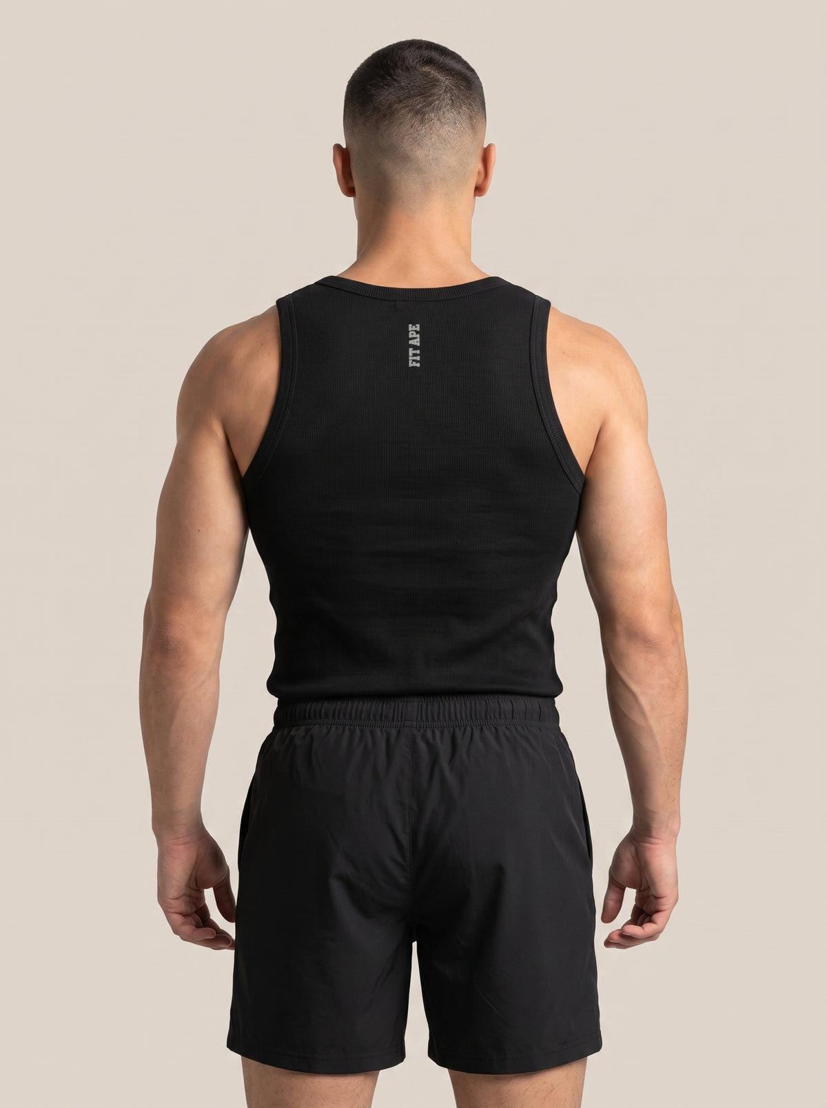 Model wearing a black FIT APE men's tank top, back view