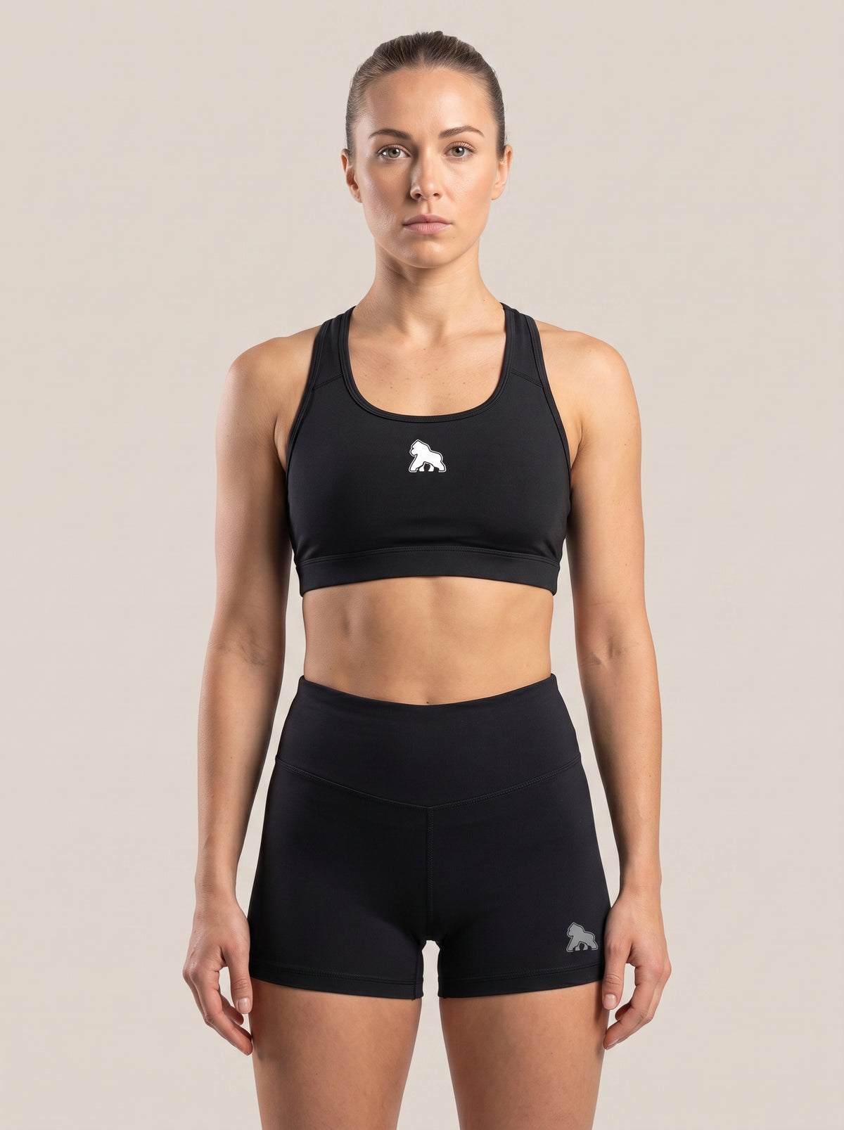 Model wearing a black FIT APE sports bra with white chest gorilla, front view