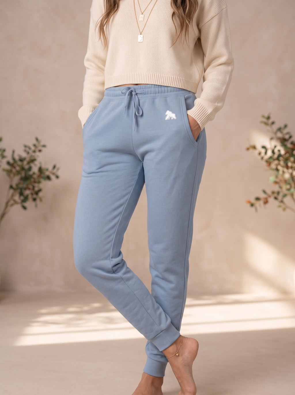 Model wearing light blue FIT APE women's sweatpants with a cream top