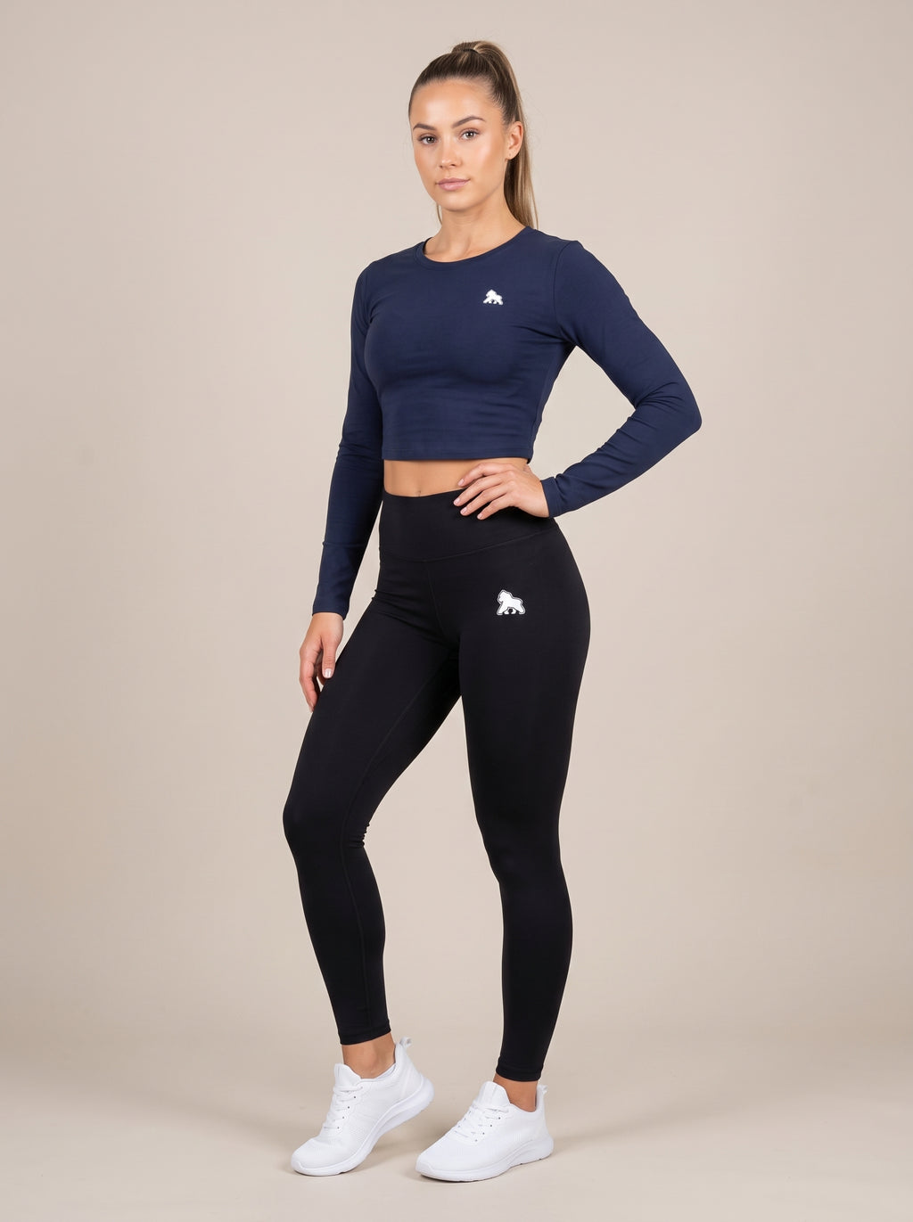 Navy FIT APE women's compression crop top on a model with one hand on her hip