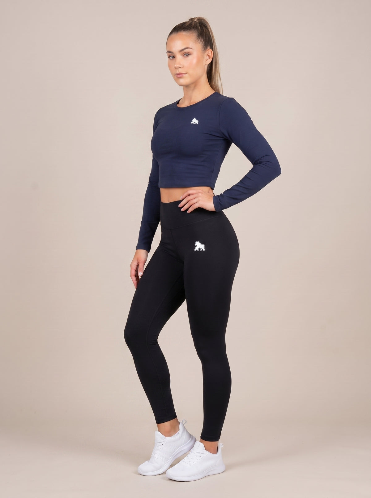 Navy FIT APE women's compression crop top on a model, front three-quarter view