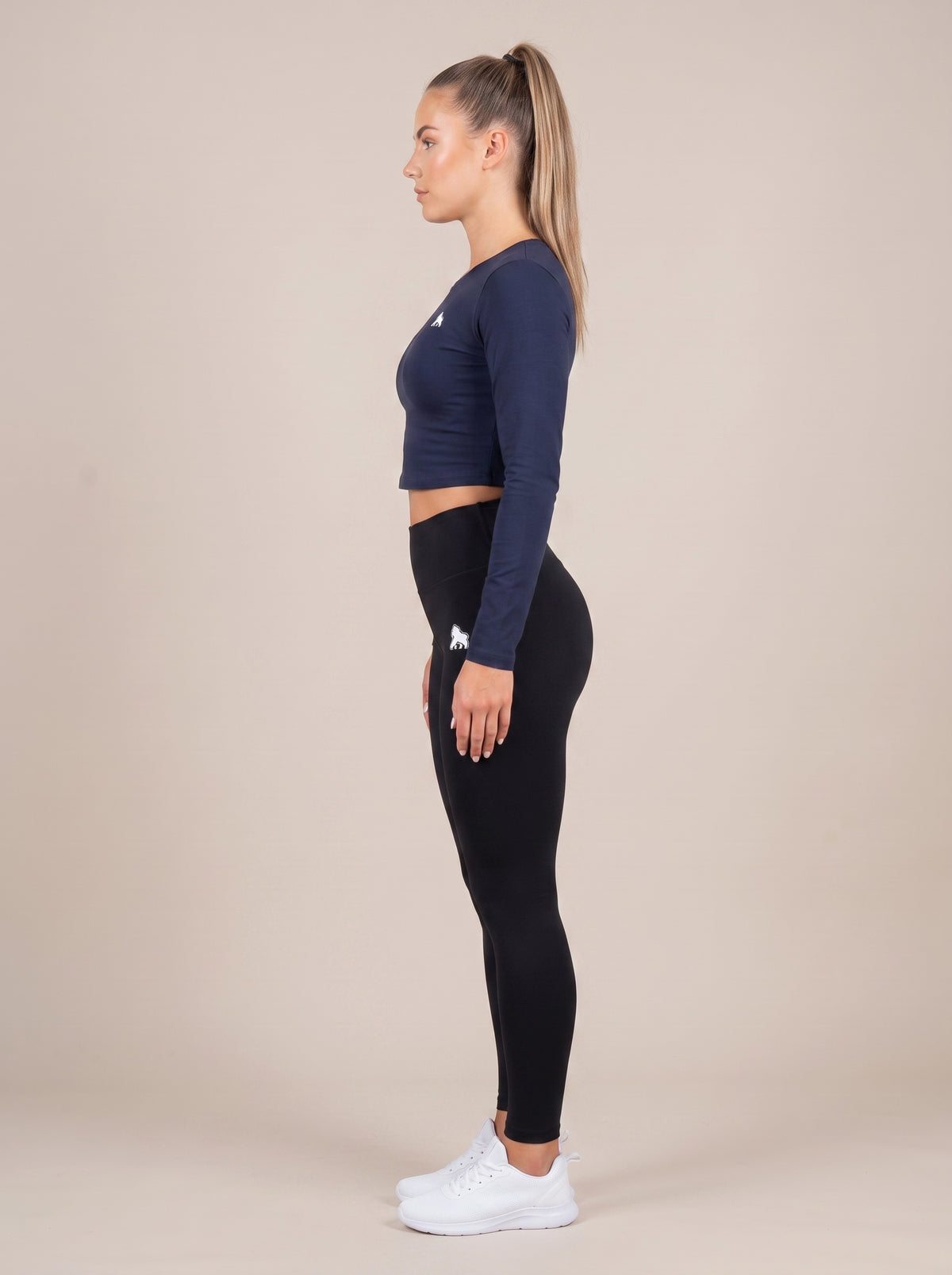 Navy FIT APE women's compression crop top on a model, side profile