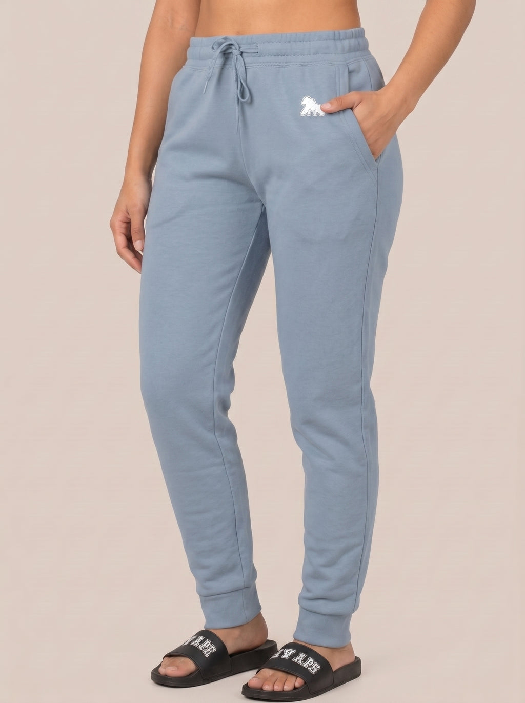 Model in blue joggers wearing black FIT APE slides, angled standing view